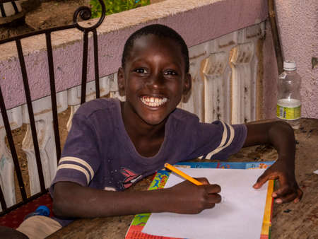 MBOUR, SENEGAL - DECEMBER Circa, 2021. Unidentified young child writing letter to godfather or...