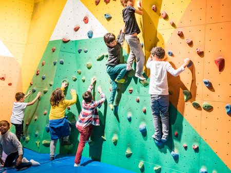 SCIENCE CENTER, PARIS, FRANCE - NOVEMBER Circa, 2019. Row of unidentified young sportswomen and schoolboy in activewear creeping upon climbing colored wall while holding by small rocksのeditorial素材