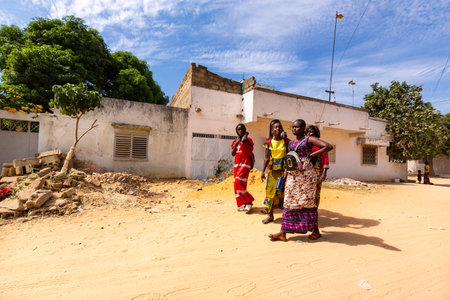 MBOUR, SENEGAL - JANUARY Circa, 2021. Unidentified school aged girls and boys students with backpack walking in the poor village after school in sunny spring day. No face mask during Covid 19 pandemic.のeditorial素材