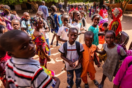 MBOUR, SENEGAL - DECEMBER Circa, 2020. Group of unidentified teenagers standing up in playground of the school, outdoors on a sunny summer day. Waiting for new bags given by international ngo. Poor rural children.のeditorial素材