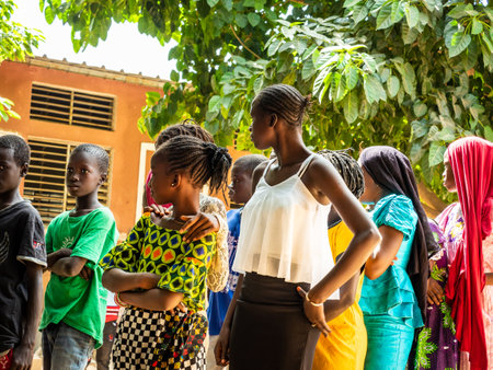 MBOUR, SENEGAL - DECEMBER Circa, 2020. Group of unidentified teenagers standing up in playground of the school, outdoors on a sunny summer day. Waiting for new bags given by international ngo. Poor rural children.のeditorial素材