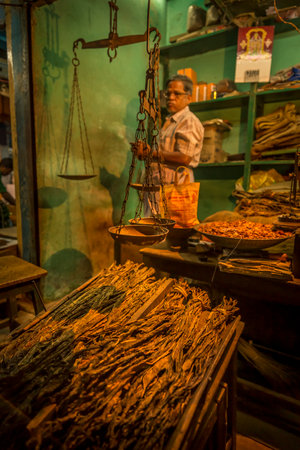 PUDUCHERRY, INDIA - March Circa, 2019. Unidentified street market vendor selling dried raw tabacco at night time. Quiet atmosphere and warm colors lights.のeditorial素材