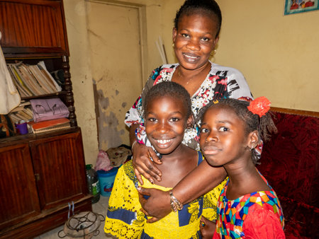 MBOUR, SENEGAL - Circa DECEMBER 2021. Unidentified women dressed with colorful traditional clothes with children in arms looking at camera samiling. Family lifestyle in village. Poverty in Africaのeditorial素材