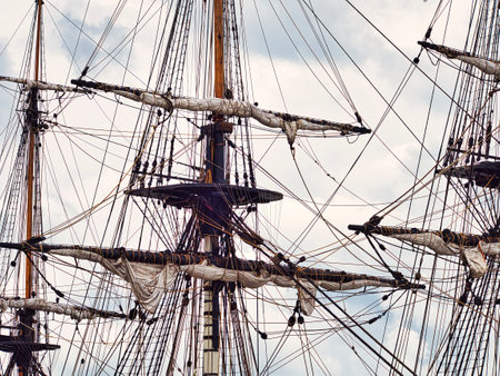 Vintage sailing ship mast ropes and tackle, Tall ship rigging mast detail, blue sky background