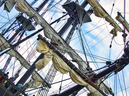 Vintage sailing ship mast ropes and tackle, Tall ship rigging mast detail, blue sky background