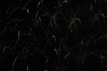 Several bright dropping fireworks in dark sky with wads of smoke