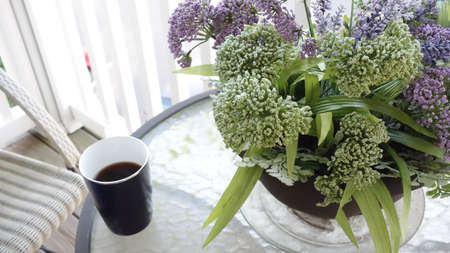 Exterior table with a cup of coffee and flowers.の写真素材