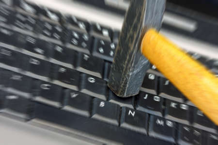 Closeup of hammer destroying laptop keyboard