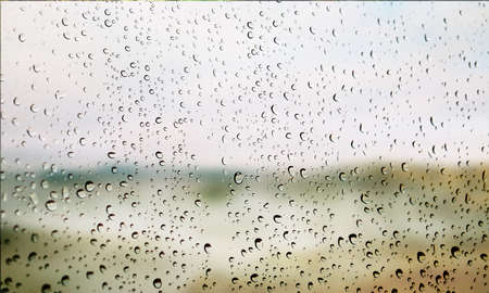 Background with rain drops close up. Rain drops on outdoor window, Closeup view transparent water drops on glass surface, humid water backdrop, blurred background with copy space for your textの写真素材