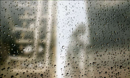 Background with rain drops close up. Rain drops on outdoor window, Closeup view transparent water drops on glass surface, humid water backdrop, blurred background with copy space for your textの写真素材