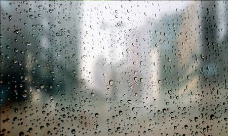 Background with rain drops close up. Rain drops on outdoor window, Closeup view transparent water drops on glass surface, humid water backdrop, blurred background with copy space for your textの写真素材