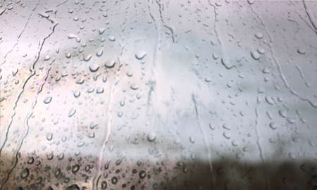 Background with rain drops close up. Rain drops on outdoor window, Closeup view transparent water drops on glass surface, humid water backdrop, blurred background with copy space for your textの写真素材