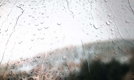 Background with rain drops close up. Rain drops on outdoor window, Closeup view transparent water drops on glass surface, humid water backdrop, blurred background with copy space for your textの写真素材