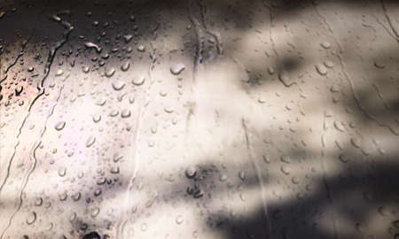 Background with rain drops close up. Rain drops on outdoor window, Closeup view transparent water drops on glass surface, humid water backdrop, blurred background with copy space for your textの写真素材