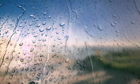Background with rain drops close up. Rain drops on outdoor window, Closeup view transparent water drops on glass surface, humid water backdrop, blurred background with copy space for your textの写真素材