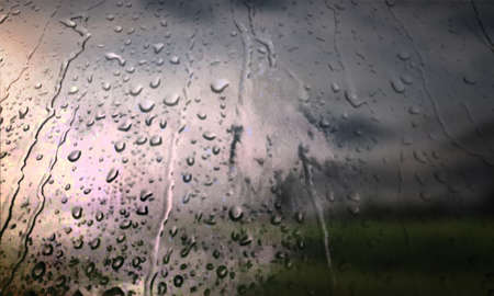 Background with rain drops close up. Rain drops on outdoor window, Closeup view transparent water drops on glass surface, humid water backdrop, blurred background with copy space for your textの写真素材