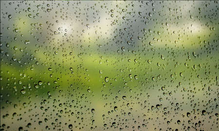 Background with rain drops close up. Rain drops on outdoor window, Closeup view transparent water drops on glass surface, humid water backdrop, blurred background with copy space for your textの写真素材