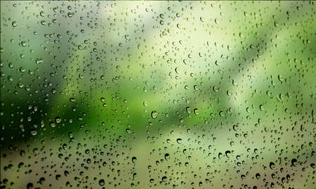 Background with rain drops close up. Rain drops on outdoor window, Closeup view transparent water drops on glass surface, humid water backdrop, blurred background with copy space for your textの写真素材