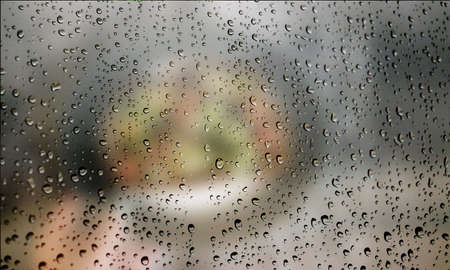 Background with rain drops close up. Rain drops on outdoor window, Closeup view transparent water drops on glass surface, humid water backdrop, blurred background with copy space for your textの写真素材