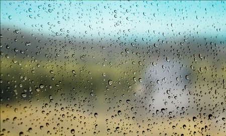 Background with rain drops close up. Rain drops on outdoor window, Closeup view transparent water drops on glass surface, humid water backdrop, blurred background with copy space for your textの写真素材