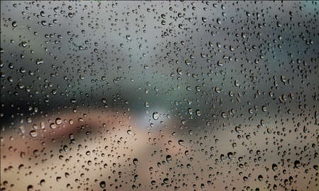 Background with rain drops close up. Rain drops on outdoor window, Closeup view transparent water drops on glass surface, humid water backdrop, blurred background with copy space for your textの写真素材