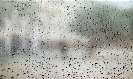 Background with rain drops close up. Rain drops on outdoor window, Closeup view transparent water drops on glass surface, humid water backdrop, blurred background with copy space for your textの写真素材