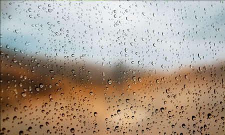 Background with rain drops close up. Rain drops on outdoor window, Closeup view transparent water drops on glass surface, humid water backdrop, blurred background with copy space for your textの写真素材