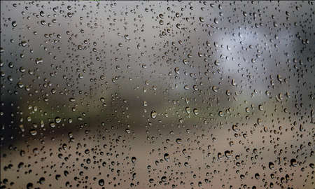 Background with rain drops close up. Rain drops on outdoor window, Closeup view transparent water drops on glass surface, humid water backdrop, blurred background with copy space for your textの写真素材