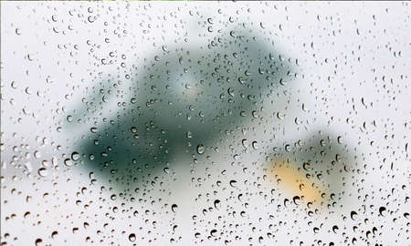 Background with rain drops close up. Rain drops on outdoor window, Closeup view transparent water drops on glass surface, humid water backdrop, blurred background with copy space for your textの写真素材