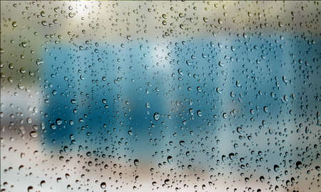 Background with rain drops close up. Rain drops on outdoor window, Closeup view transparent water drops on glass surface, humid water backdrop, blurred background with copy space for your textの写真素材