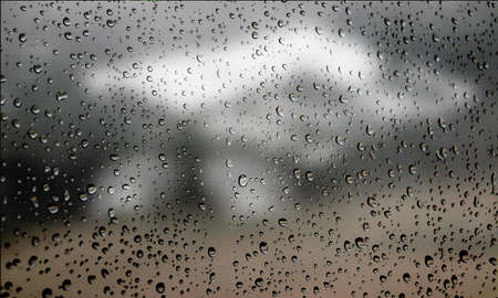 Background with rain drops close up. Rain drops on outdoor window, Closeup view transparent water drops on glass surface, humid water backdrop, blurred background with copy space for your textの写真素材