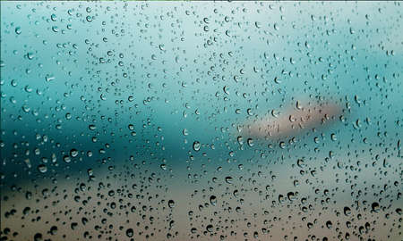 Background with rain drops close up. Rain drops on outdoor window, Closeup view transparent water drops on glass surface, humid water backdrop, blurred background with copy space for your textの写真素材