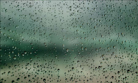 Background with rain drops close up. Rain drops on outdoor window, Closeup view transparent water drops on glass surface, humid water backdrop, blurred background with copy space for your textの写真素材