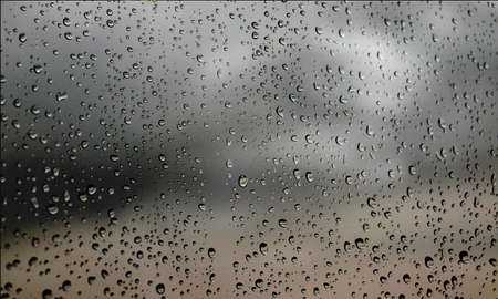 Background with rain drops close up. Rain drops on outdoor window, Closeup view transparent water drops on glass surface, humid water backdrop, blurred background with copy space for your textの写真素材
