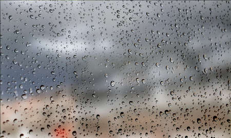 Background with rain drops close up. Rain drops on outdoor window, Closeup view transparent water drops on glass surface, humid water backdrop, blurred background with copy space for your textの写真素材