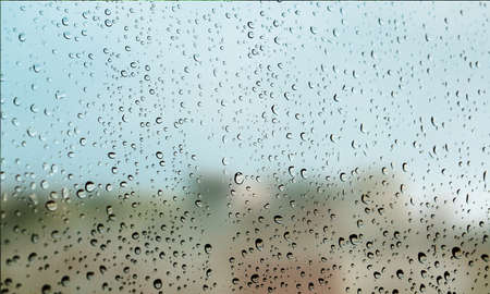 Background with rain drops close up. Rain drops on outdoor window, Closeup view transparent water drops on glass surface, humid water backdrop, blurred background with copy space for your textの写真素材