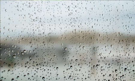 Background with rain drops close up. Rain drops on outdoor window, Closeup view transparent water drops on glass surface, humid water backdrop, blurred background with copy space for your textの写真素材