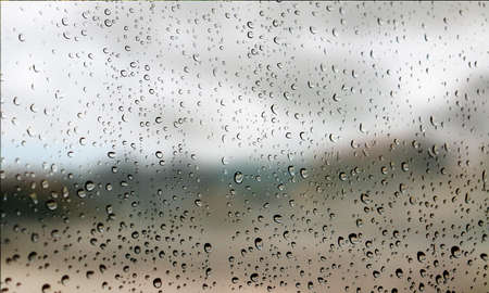 Background with rain drops close up. Rain drops on outdoor window, Closeup view transparent water drops on glass surface, humid water backdrop, blurred background with copy space for your textの写真素材