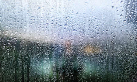 Water drops on window glass with blurred background. Rainy weather concept.
