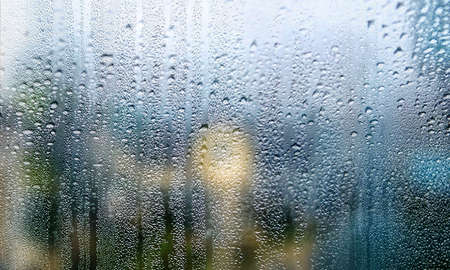 Background with rain drops on glass, closeup view. Rain drops on outdoor window, humid water...