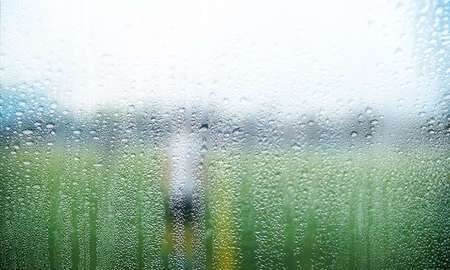 Rain drops on the window with a blurred background of the field.