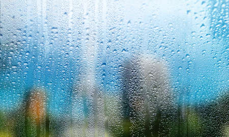 Water drops on the glass, blurred background. Rainy weather concept