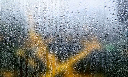 Water drops on window glass, rainy weather background, close up.