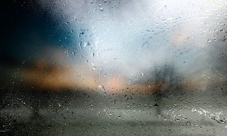 Rain drops on window glass with blurred background. Rainy weather.の写真素材