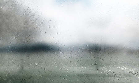 Rain drops on glass with blurred background. Rainy weather concept.