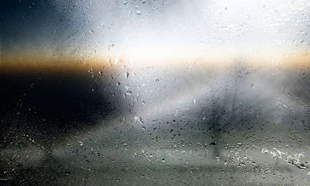 Rain drops on the window. Rainy weather. The sun behind the glass.