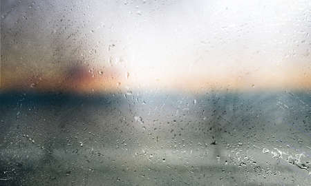 Water drops on glass with blurred background. Rainy weather concept.