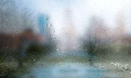 Drops of rain on the window, blurred cityscape background.