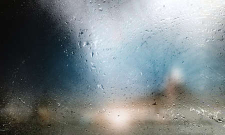 Water drops on glass with blurred background. Rainy weather concept.