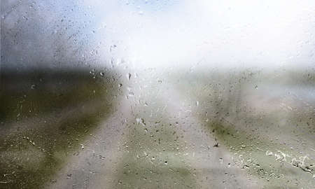 Water drops on the glass with a blurred road in the background.